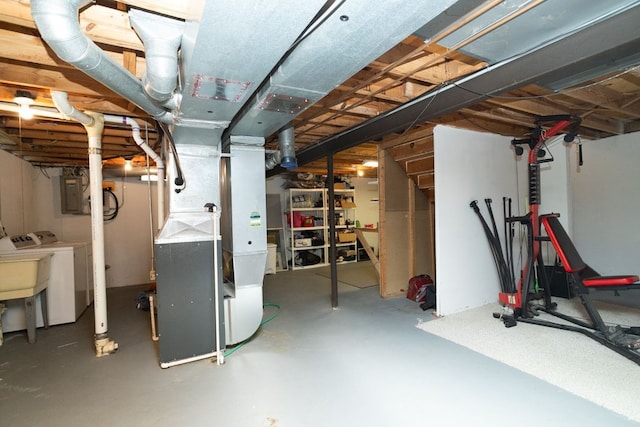 unfinished basement featuring heating unit, electric panel, and washer and clothes dryer
