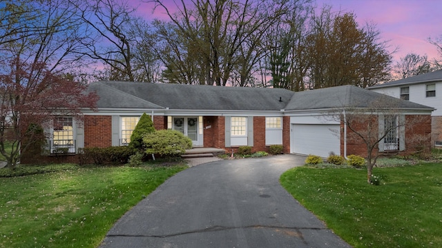 single story home with driveway, a lawn, an attached garage, and brick siding