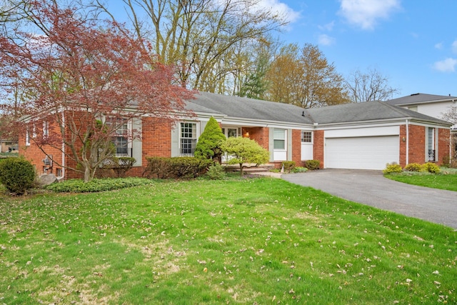 single story home featuring driveway, a front lawn, brick siding, and an attached garage
