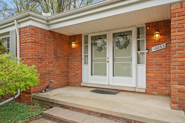property entrance featuring covered porch and brick siding
