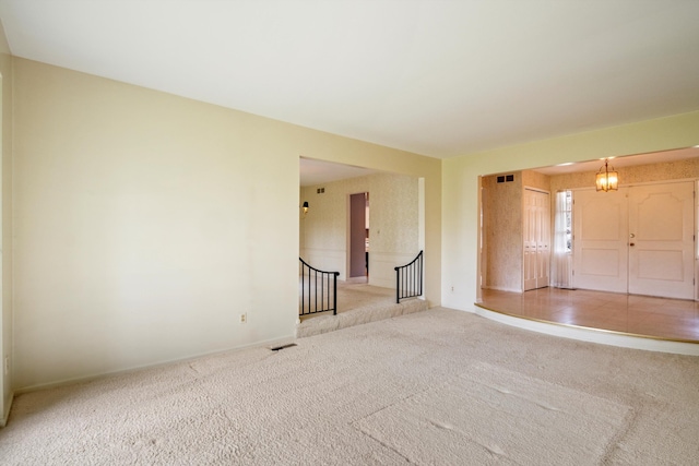 unfurnished room with carpet, visible vents, and baseboards