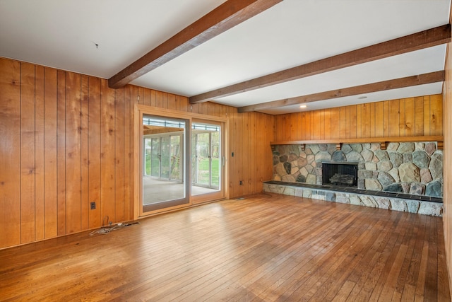 unfurnished living room with wood walls, beam ceiling, and hardwood / wood-style flooring