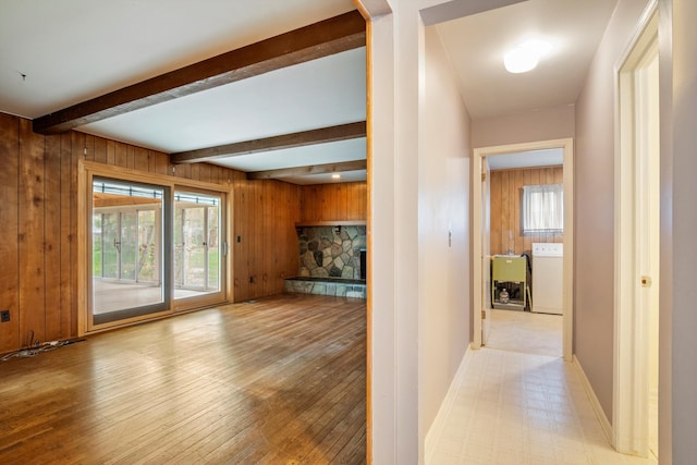 hall with beamed ceiling, wood walls, baseboards, light wood finished floors, and washer / dryer