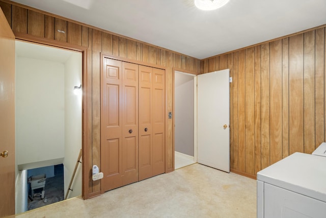 laundry room featuring washing machine and clothes dryer, light carpet, wood walls, and laundry area