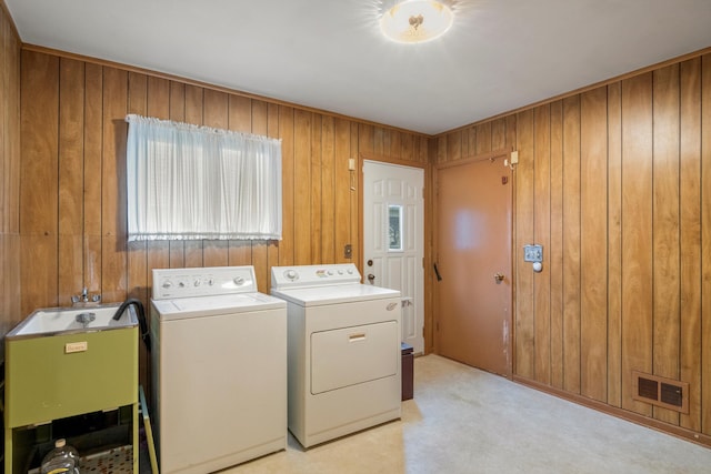 washroom with laundry area, visible vents, wood walls, light carpet, and washer and dryer