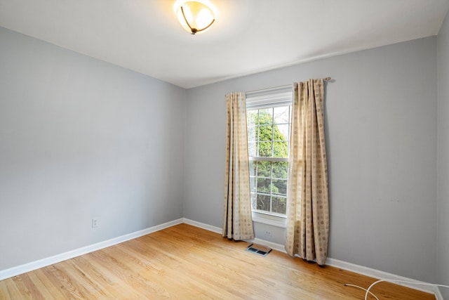 spare room featuring visible vents, wood finished floors, and baseboards