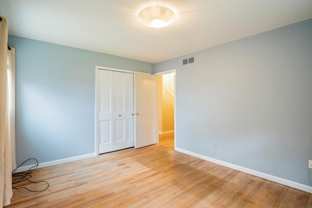 unfurnished bedroom featuring visible vents, a closet, light wood-style flooring, and baseboards
