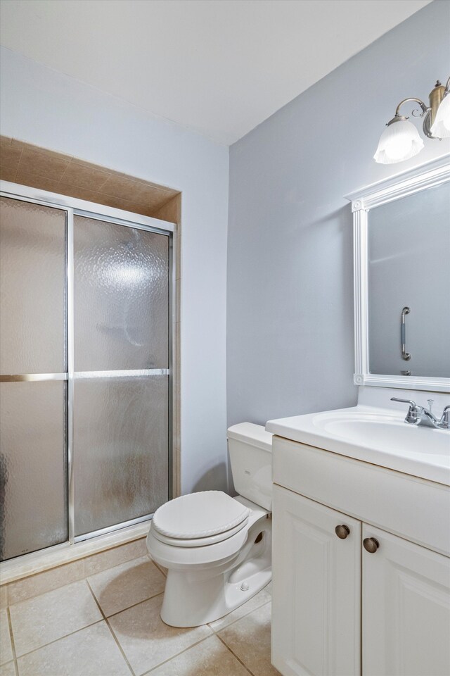 bathroom with toilet, a stall shower, tile patterned floors, and vanity