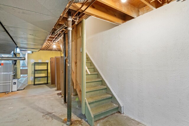unfinished basement with stairway and heating unit