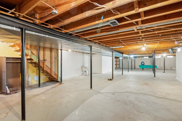 unfinished basement featuring stairs and a sink