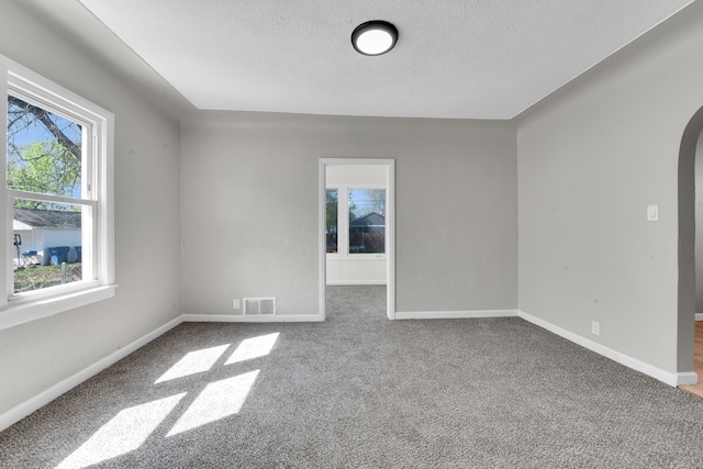 8127 Continental Ave, Warren, MI 48089 - carpeted spare room with arched walkways, visible vents, a textured ceiling, and baseboards