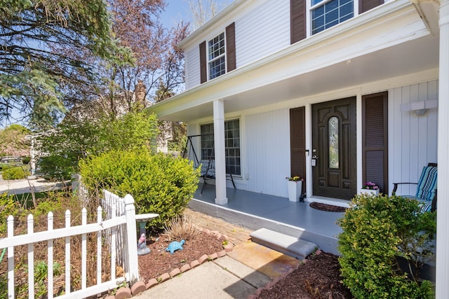 doorway to property with a porch and fence