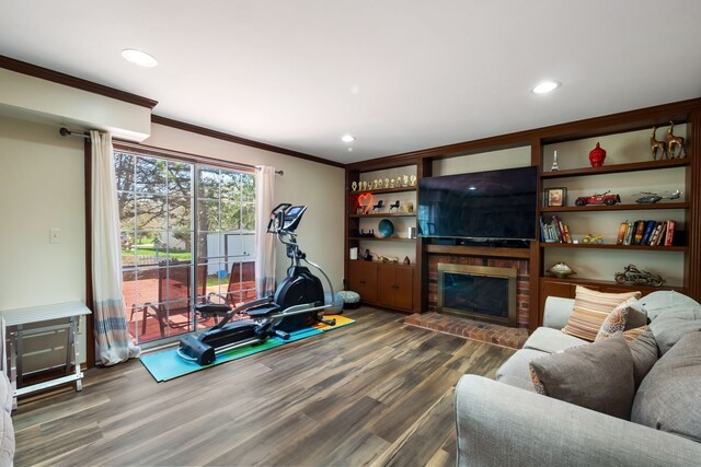 workout area featuring recessed lighting, ornamental molding, wood finished floors, and a fireplace