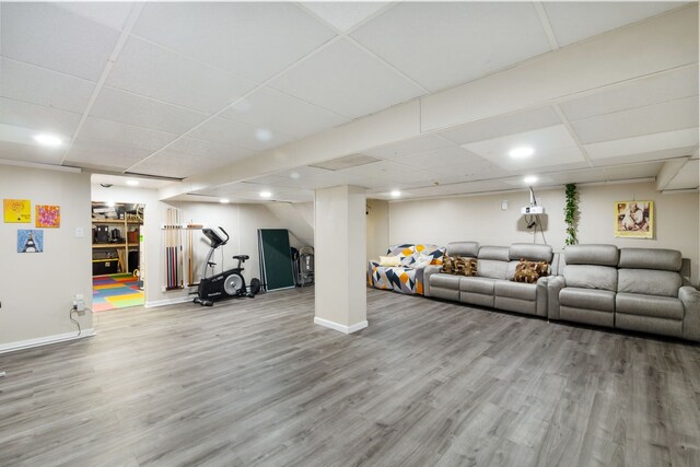 living room with baseboards, a drop ceiling, and wood finished floors