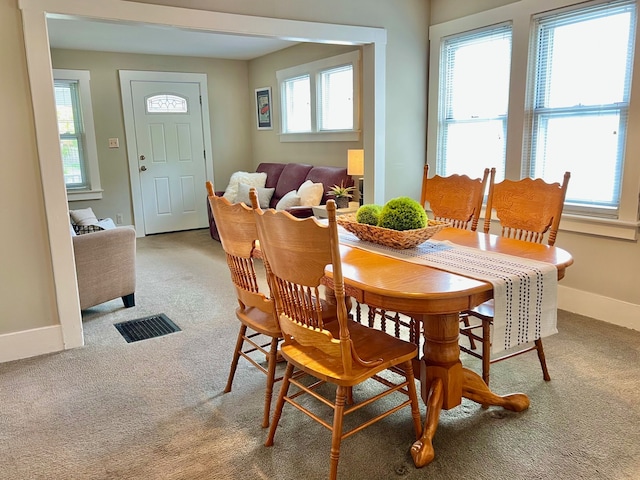 carpeted dining room with baseboards and visible vents