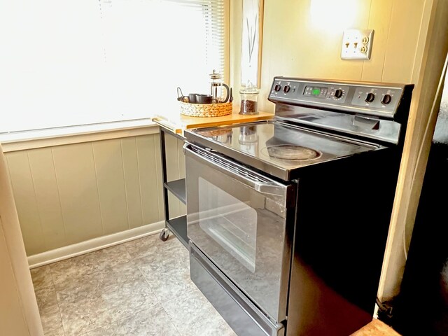 kitchen with electric stove, wainscoting, and a decorative wall