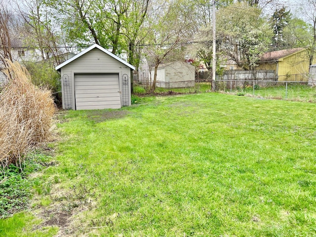 view of yard with an outbuilding, a detached garage, and fence