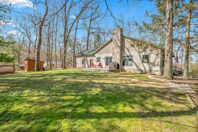3553 Alpine Ct, Hillsdale, MI 49242 - back of house with a wooden deck, an outbuilding, a yard, a shed, and a chimney
