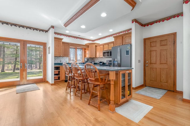 3553 Alpine Ct, Hillsdale, MI 49242 - kitchen featuring light wood finished floors, stainless steel appliances, tasteful backsplash, a center island, and a breakfast bar area