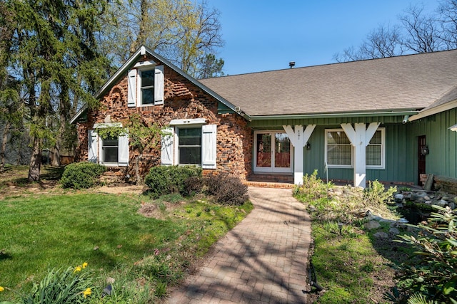 view of front of home featuring roof with shingles, board and batten siding, and a front yard