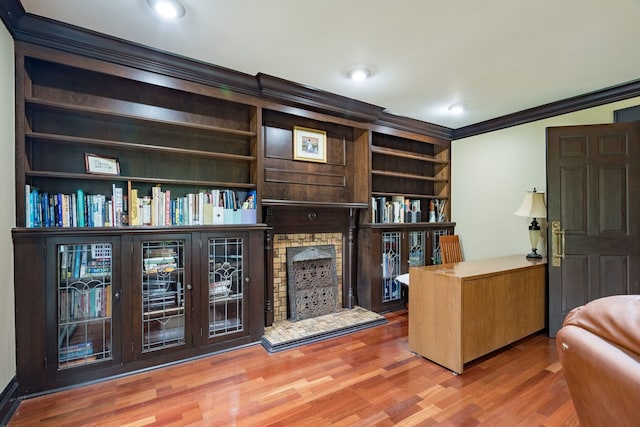 interior space featuring crown molding, a fireplace with raised hearth, recessed lighting, and wood finished floors