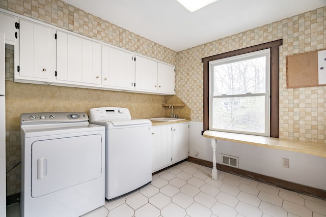 laundry area featuring a sink, separate washer and dryer, cabinet space, and visible vents