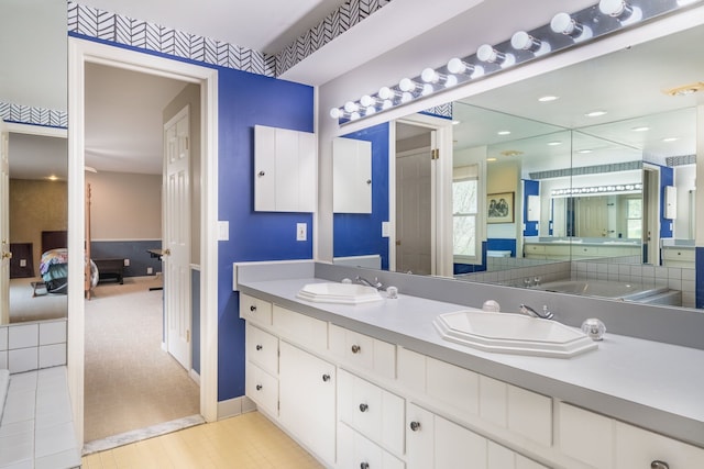 bathroom featuring double vanity, a sink, and ensuite bath