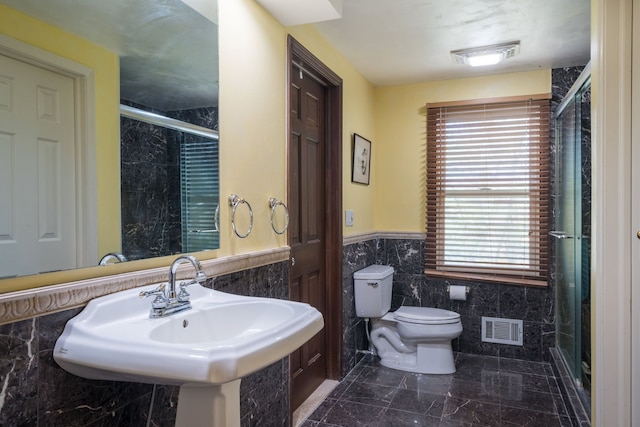 bathroom featuring a sink, toilet, plenty of natural light, tile walls, and visible vents