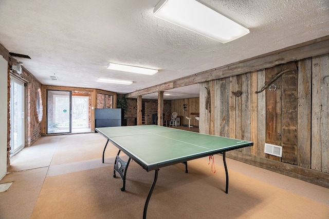 playroom featuring wood walls, a textured ceiling, and visible vents