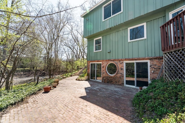 rear view of property with a patio, board and batten siding, and brick siding
