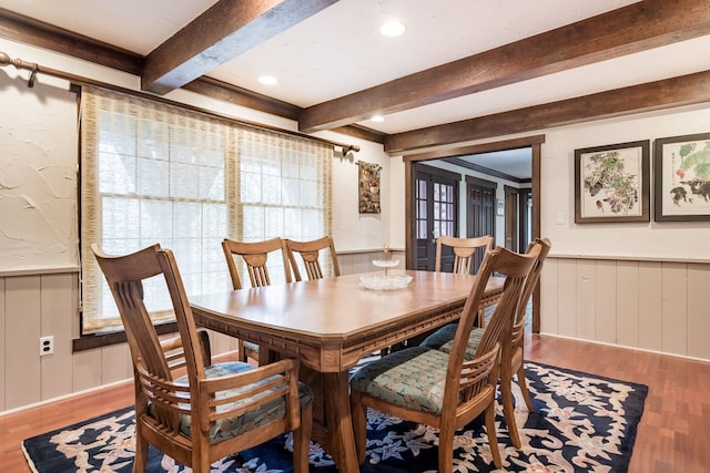 dining space featuring a wainscoted wall, wood finished floors, and beamed ceiling