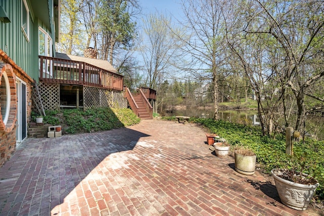 view of patio / terrace with a deck with water view and stairway