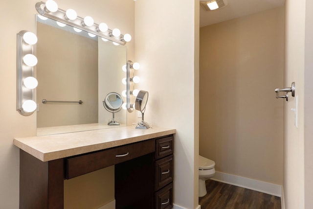 bathroom featuring baseboards, wood finished floors, toilet, and vanity