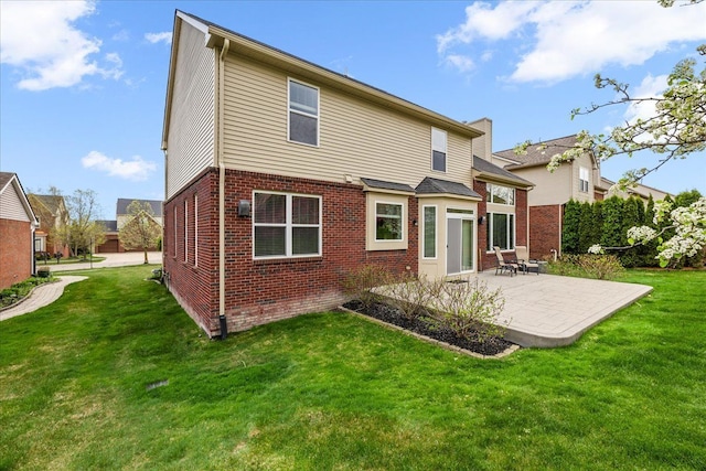 back of property featuring brick siding, a yard, and a patio