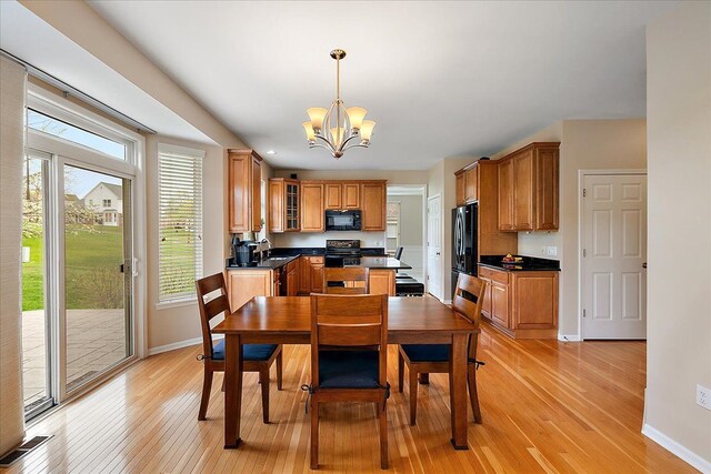 dining space with baseboards, light wood-type flooring, and a notable chandelier