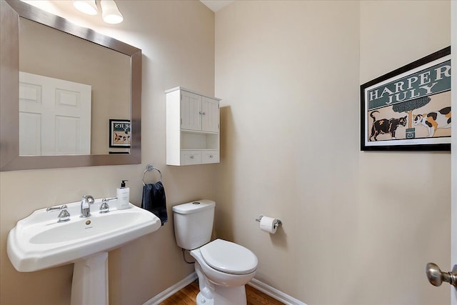 bathroom with a sink, baseboards, toilet, and wood finished floors