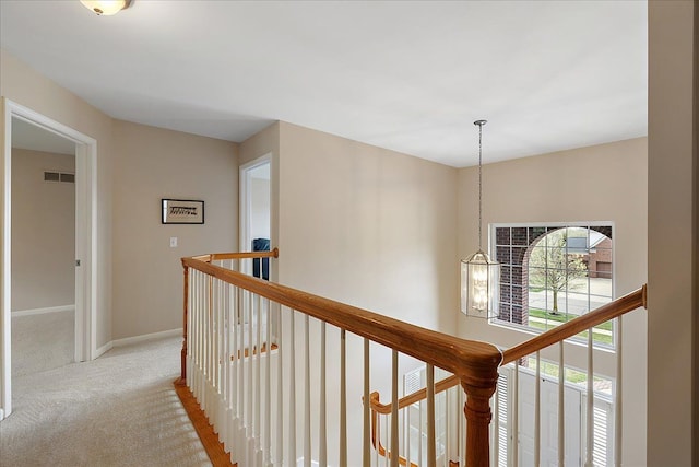 hallway featuring baseboards, an upstairs landing, light carpet, and visible vents