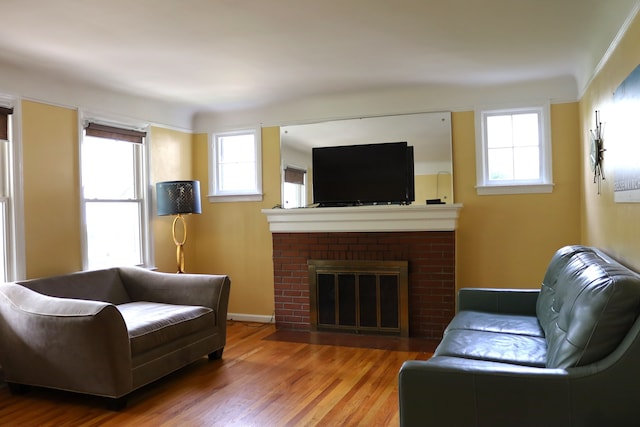 living area with a brick fireplace, plenty of natural light, and wood finished floors