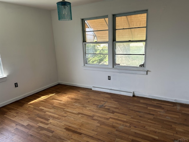 unfurnished room with baseboards, a baseboard heating unit, and wood finished floors
