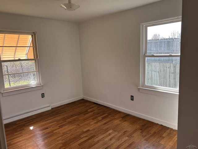 empty room featuring baseboards, plenty of natural light, baseboard heating, and wood finished floors