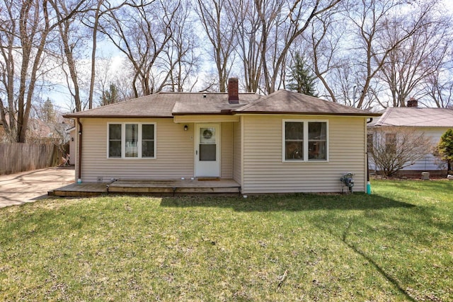 view of front facade featuring a front yard, a deck, a chimney, and fence