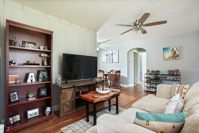 living room featuring wood finished floors, ceiling fan, and arched walkways