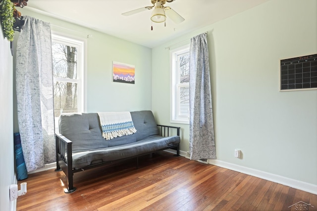 living area featuring a ceiling fan, hardwood / wood-style floors, a wealth of natural light, and baseboards