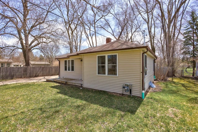 back of property featuring a lawn, a chimney, and a fenced backyard