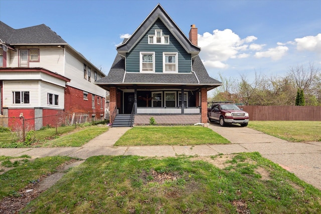 view of front facade with roof with shingles, covered porch, a chimney, and a front yard