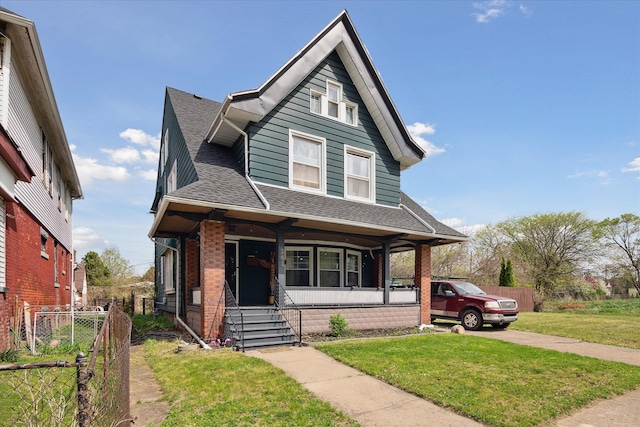 bungalow-style home with fence, a front yard, brick siding, a shingled roof, and a porch