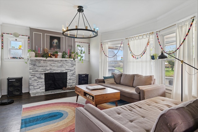 living room with an inviting chandelier, ornamental molding, wood finished floors, and a fireplace