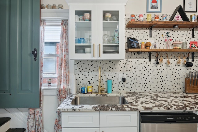 kitchen featuring backsplash, open shelves, stainless steel dishwasher, a sink, and white cabinets