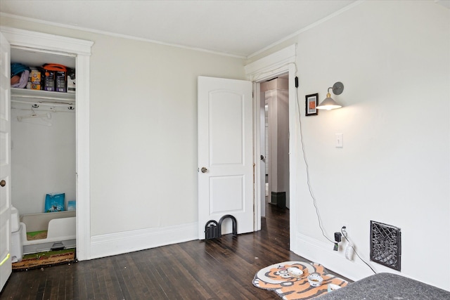 bedroom with baseboards, ornamental molding, wood finished floors, and visible vents