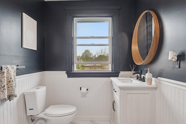 bathroom with a healthy amount of sunlight, vanity, wainscoting, and toilet